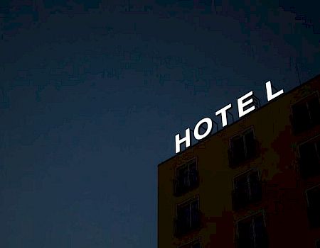 A building with an illuminated "HOTEL" sign against a dark twilight sky.